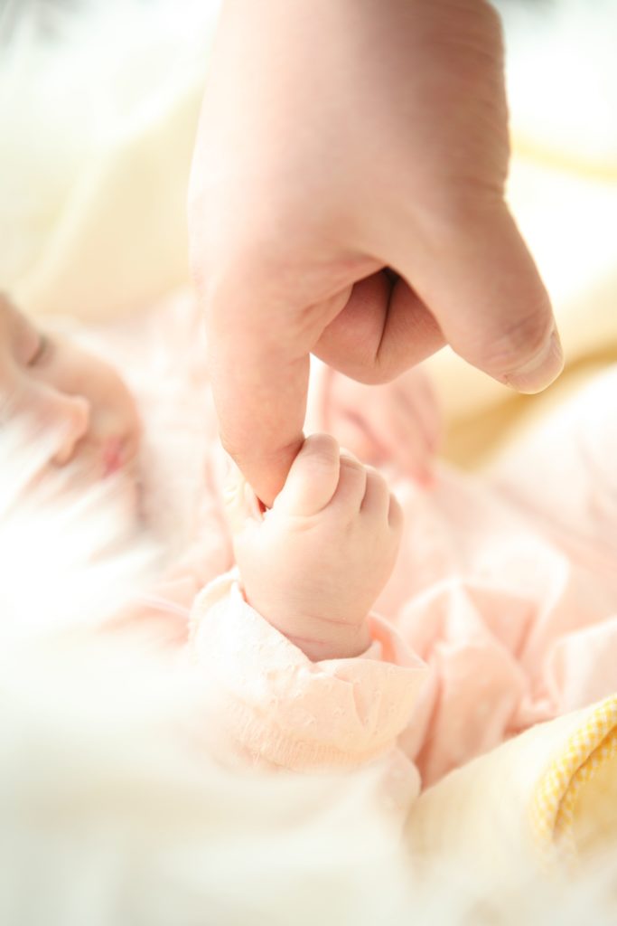 bébé endormi paisiblement attrapant le doigt de son parent